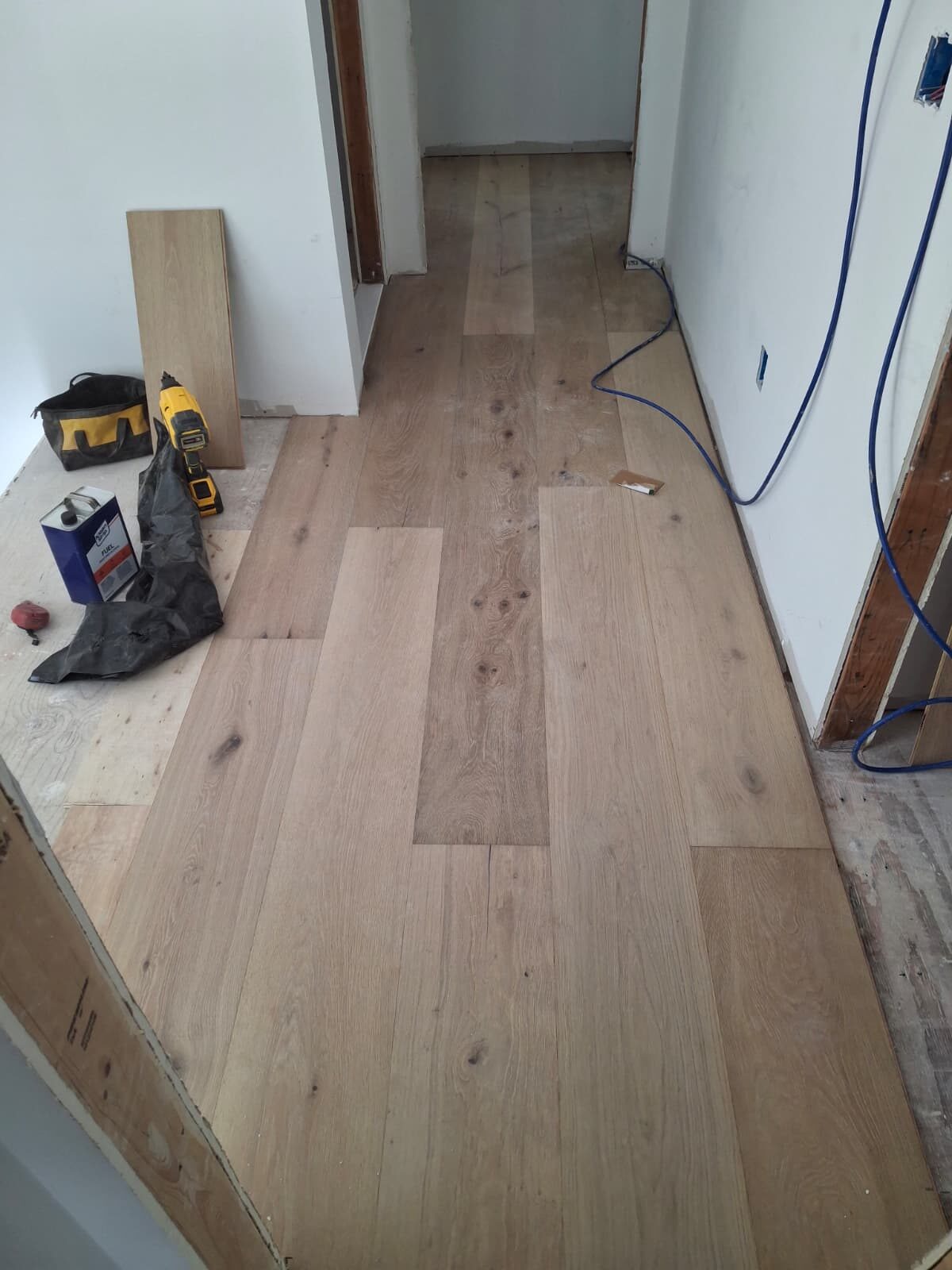 Wide-plank glue-down engineered hardwood installation in a hallway